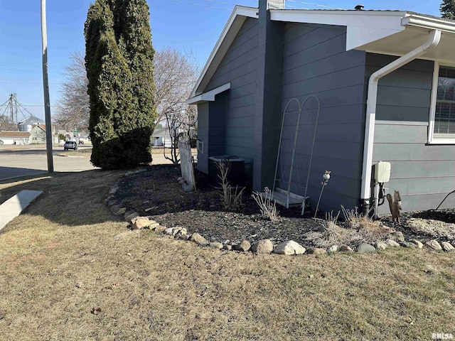 view of side of home with central AC unit and a chimney