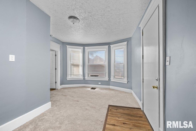 unfurnished bedroom with carpet flooring, visible vents, baseboards, and a textured ceiling