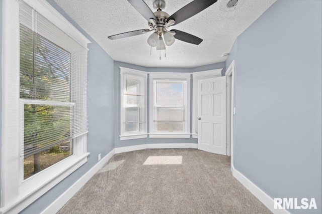 empty room featuring a textured ceiling, a ceiling fan, baseboards, and carpet floors