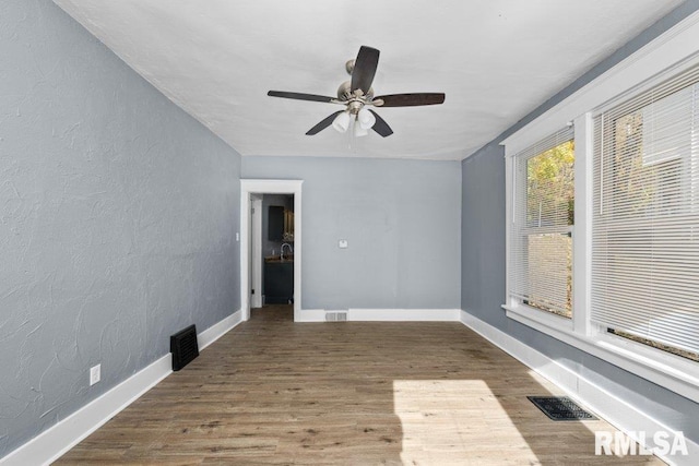 spare room with wood finished floors, visible vents, and baseboards