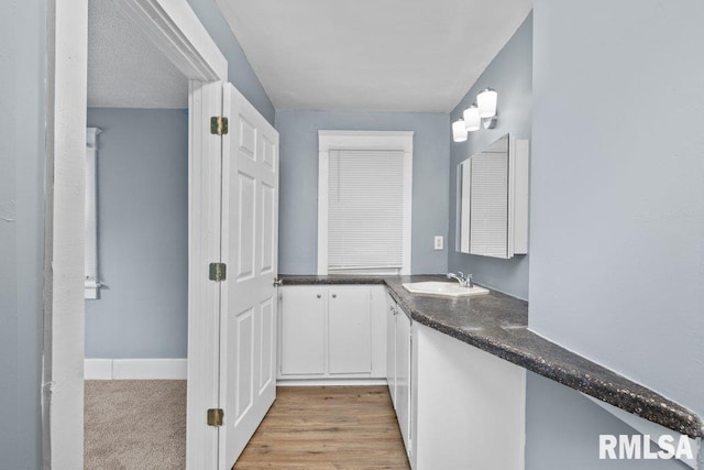 interior space with vanity, baseboards, and wood finished floors