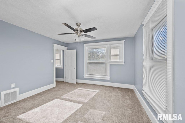 unfurnished bedroom featuring baseboards, visible vents, carpet floors, ceiling fan, and a textured ceiling