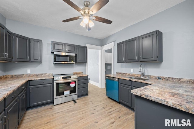 kitchen featuring light countertops, appliances with stainless steel finishes, light wood-style floors, a ceiling fan, and a sink