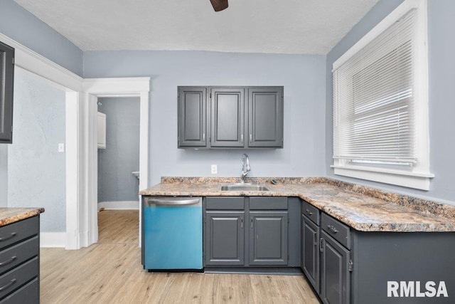 kitchen featuring a sink, dishwashing machine, light wood-type flooring, and gray cabinetry