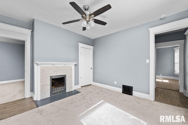 unfurnished living room featuring visible vents, a ceiling fan, carpet floors, a fireplace, and baseboards