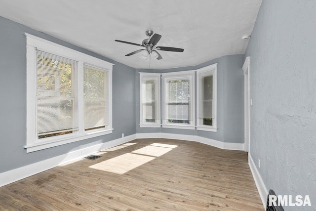 unfurnished room featuring a ceiling fan, wood finished floors, and baseboards