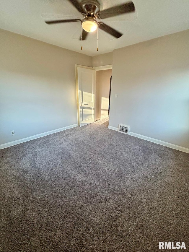 carpeted spare room featuring baseboards, visible vents, and ceiling fan