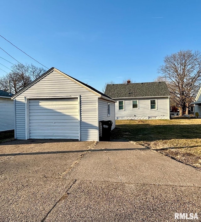 exterior space featuring an outbuilding, driveway, a front lawn, and a garage