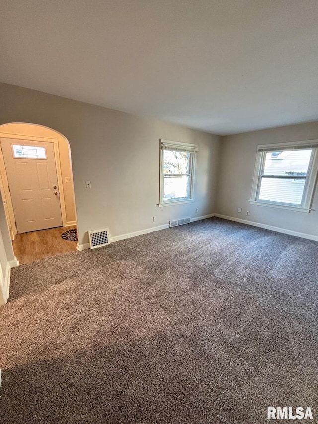 spare room with visible vents, baseboards, carpet, and arched walkways