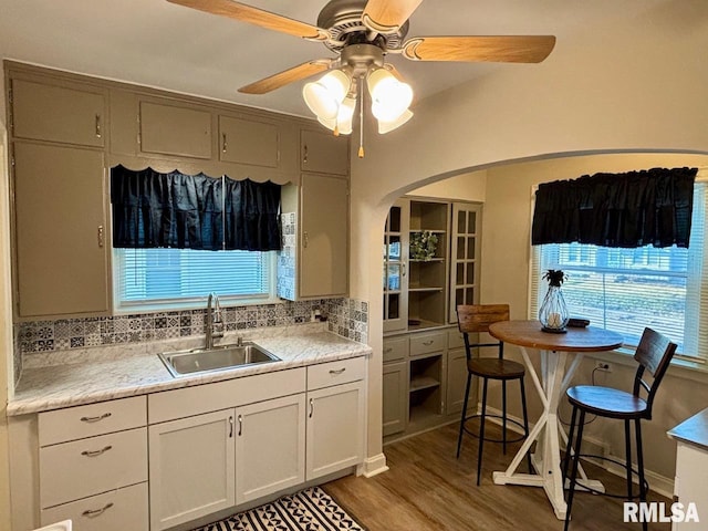 kitchen with light wood-style flooring, a sink, light countertops, decorative backsplash, and ceiling fan