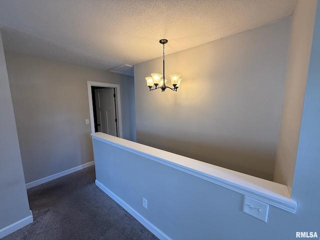 hallway featuring a chandelier, carpet flooring, a textured ceiling, and baseboards