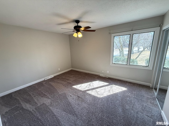 empty room with visible vents, a textured ceiling, carpet flooring, baseboards, and ceiling fan