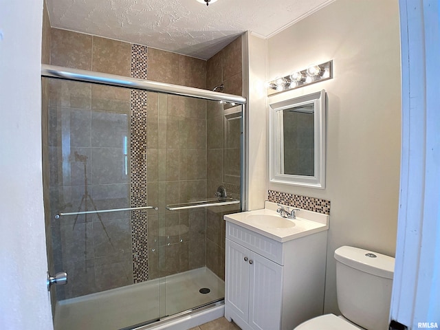 bathroom with vanity, toilet, a stall shower, and a textured ceiling