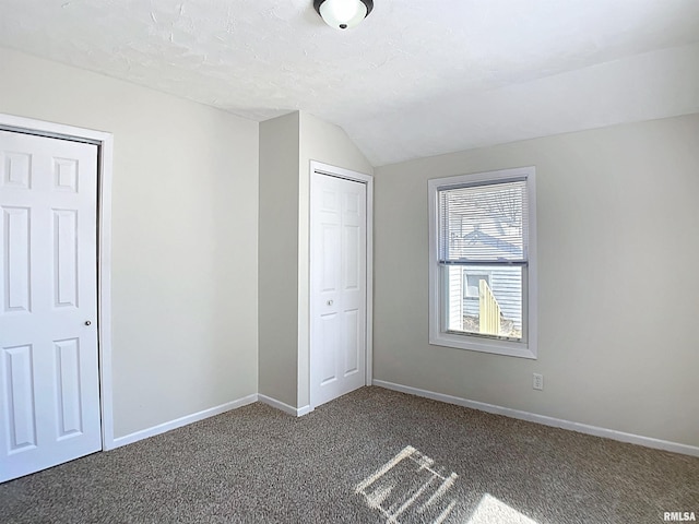 unfurnished bedroom with lofted ceiling, carpet flooring, and baseboards