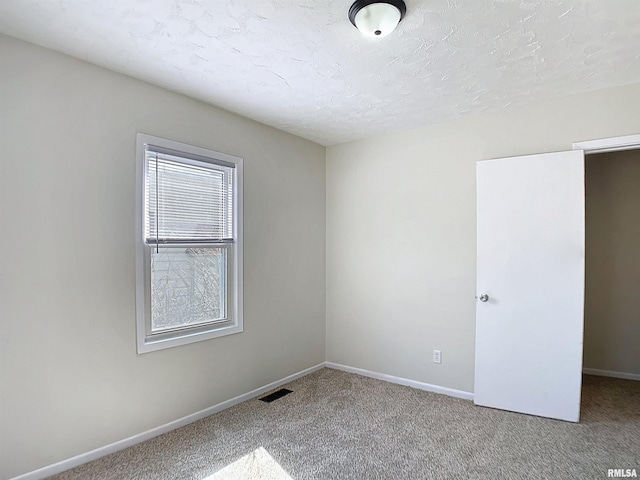 empty room featuring visible vents, a textured ceiling, baseboards, and carpet floors