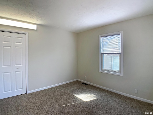 empty room with visible vents, baseboards, and carpet