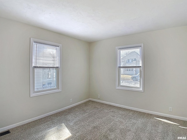 carpeted spare room featuring visible vents and baseboards