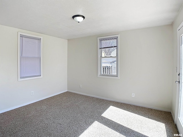 carpeted empty room with a textured ceiling and baseboards