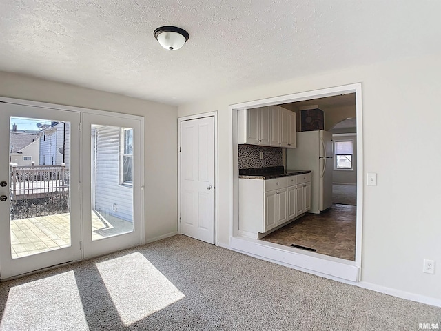 kitchen featuring dark countertops, carpet flooring, a textured ceiling, and freestanding refrigerator