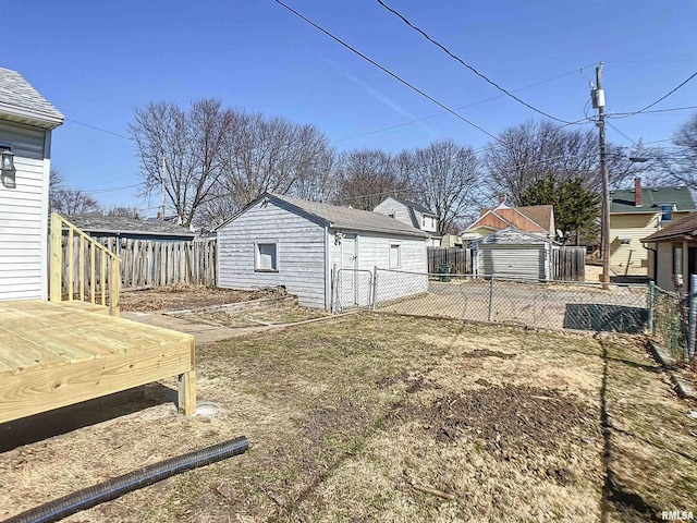 view of yard with an outbuilding, a garage, a fenced backyard, and a deck