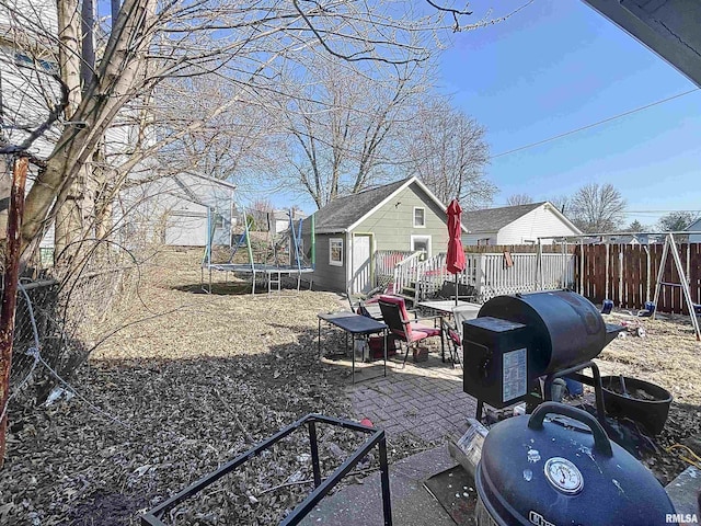 view of yard featuring an outbuilding, a patio, a trampoline, a playground, and fence