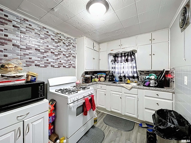 kitchen featuring white range with gas cooktop, light wood-style floors, tile walls, and black microwave