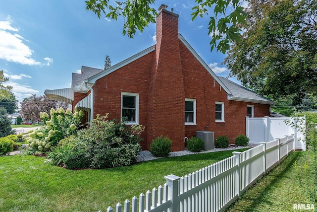 view of side of property with cooling unit, fence, a chimney, a lawn, and brick siding