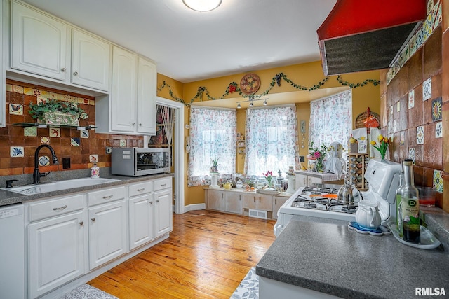 kitchen with tasteful backsplash, visible vents, light wood-style flooring, white appliances, and a sink