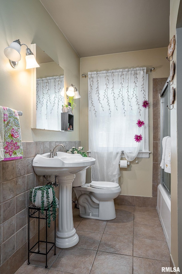 full bathroom with tile patterned flooring, toilet, wainscoting, shower / bath combination with glass door, and tile walls