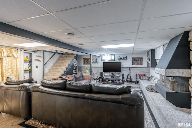 living room featuring stairs, a paneled ceiling, and visible vents