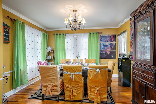 dining space with crown molding, a notable chandelier, wood finished floors, and a wealth of natural light