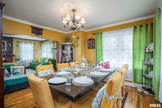 dining room featuring crown molding, wood finished floors, arched walkways, and a chandelier