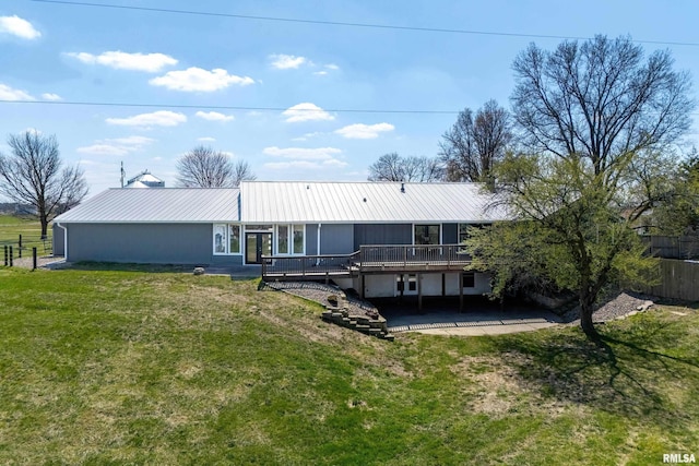 back of house with a wooden deck, a lawn, metal roof, a patio area, and fence