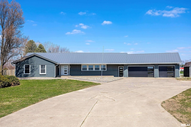 ranch-style home featuring concrete driveway, an attached garage, a front lawn, and metal roof