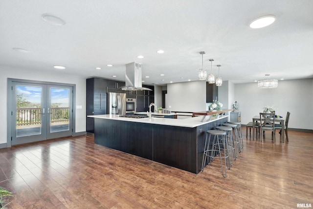 kitchen featuring wood finished floors, island exhaust hood, light countertops, and stainless steel appliances