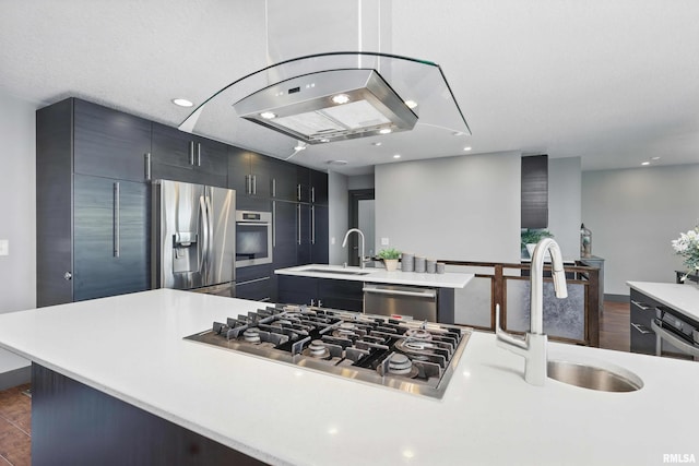 kitchen with stainless steel appliances, a kitchen island with sink, light countertops, and a sink