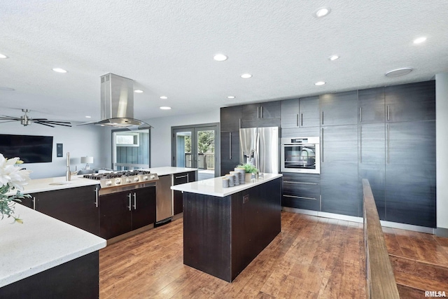 kitchen featuring island exhaust hood, light countertops, a kitchen island, and stainless steel appliances