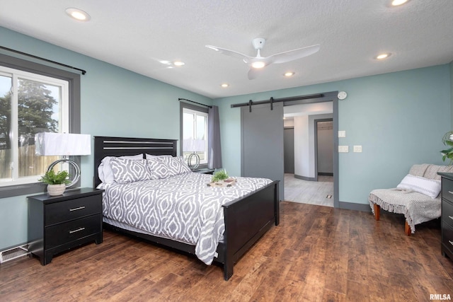 bedroom featuring recessed lighting, multiple windows, a barn door, and wood finished floors