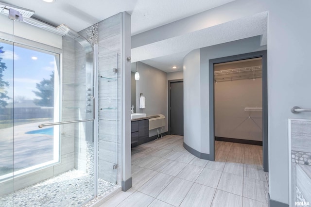 bathroom with a shower stall, vanity, and a spacious closet