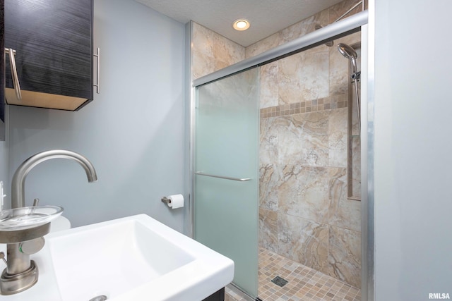 bathroom with a stall shower and a sink