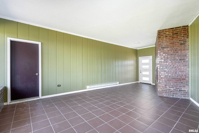 interior space with baseboard heating, dark tile patterned flooring, crown molding, and baseboards