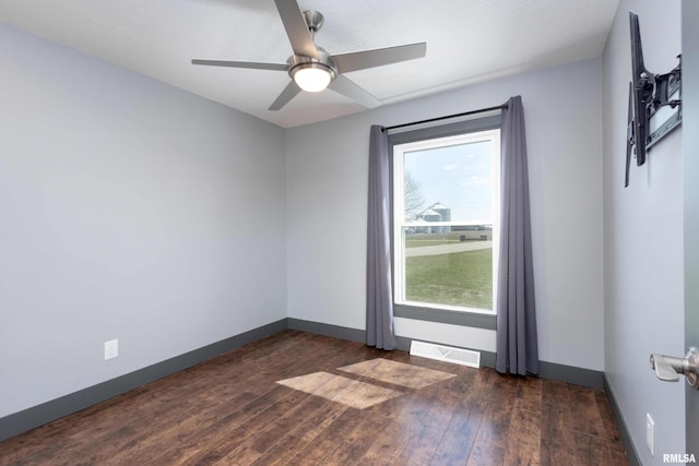 unfurnished room with ceiling fan, visible vents, baseboards, and dark wood finished floors