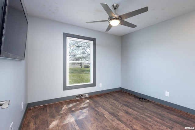 unfurnished room featuring ceiling fan, baseboards, dark wood finished floors, and visible vents
