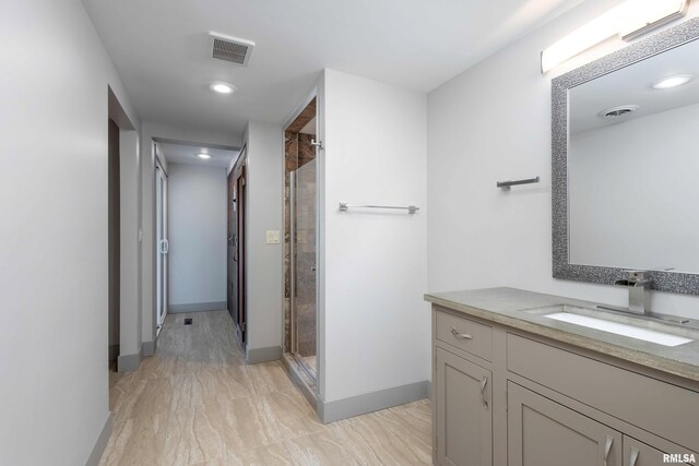 bathroom with a stall shower, vanity, baseboards, and visible vents