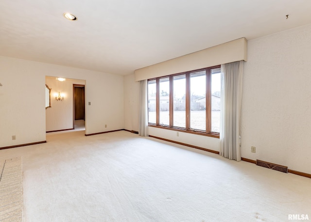 unfurnished room with light carpet, visible vents, and baseboards