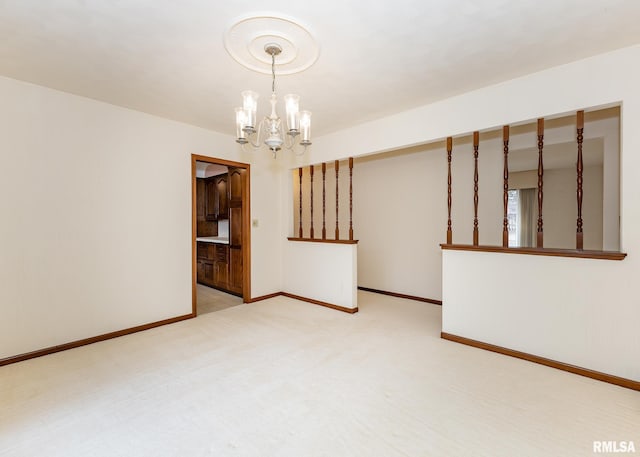 spare room with a notable chandelier, light colored carpet, and baseboards