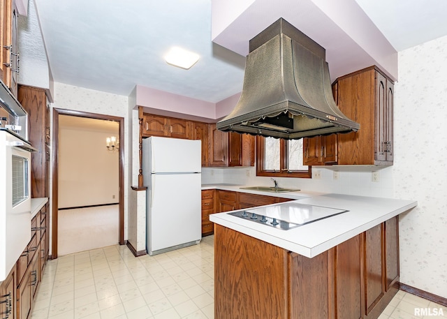 kitchen featuring wallpapered walls, a peninsula, island exhaust hood, brown cabinetry, and white appliances