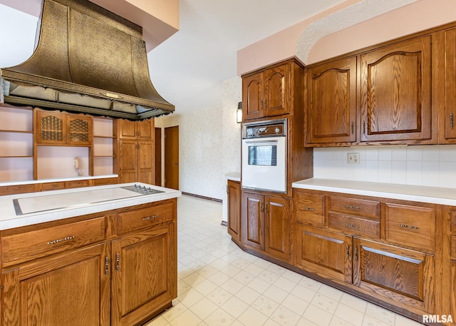 kitchen featuring premium range hood, light floors, brown cabinetry, white appliances, and open shelves