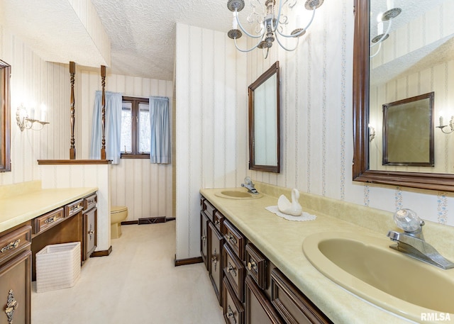 full bathroom featuring wallpapered walls, double vanity, a sink, a textured ceiling, and a notable chandelier