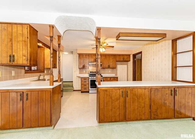 9721 234th St N, Port Byron, IL 61275 - kitchen with stainless steel gas range, brown cabinets, a peninsula, a ceiling fan, and tasteful backsplash